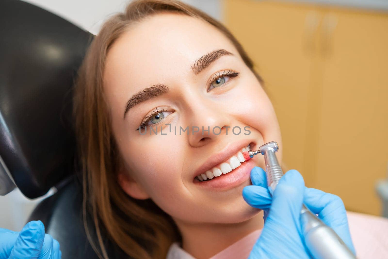 Dentist doing procedure of teeth grinding to beautiful woman in dental clinic.