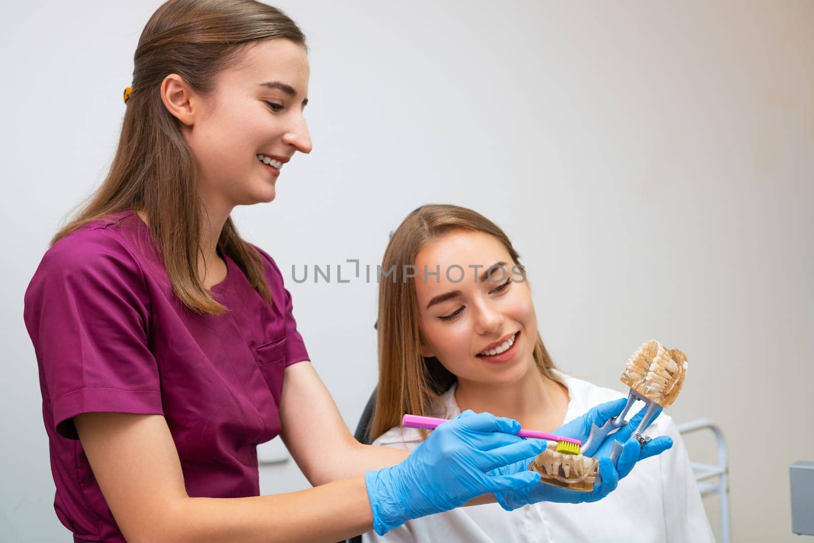 A skilled dental hygienist instructs a young woman on the way of teeth cleaning. by vladimka