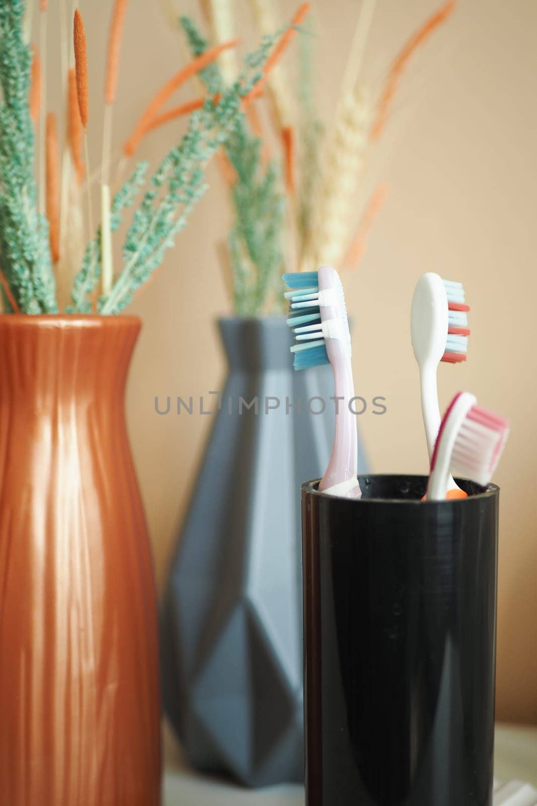 colorful toothbrushes in white mug against a wall .