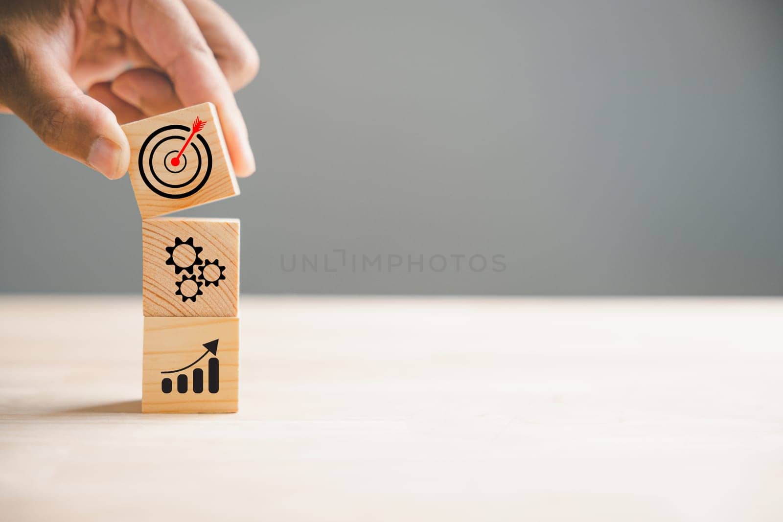 Hand holding and arranging wood blocks in a stacking formation, representing a business strategy and Action plan. This image illustrates the concept of business development and growth.