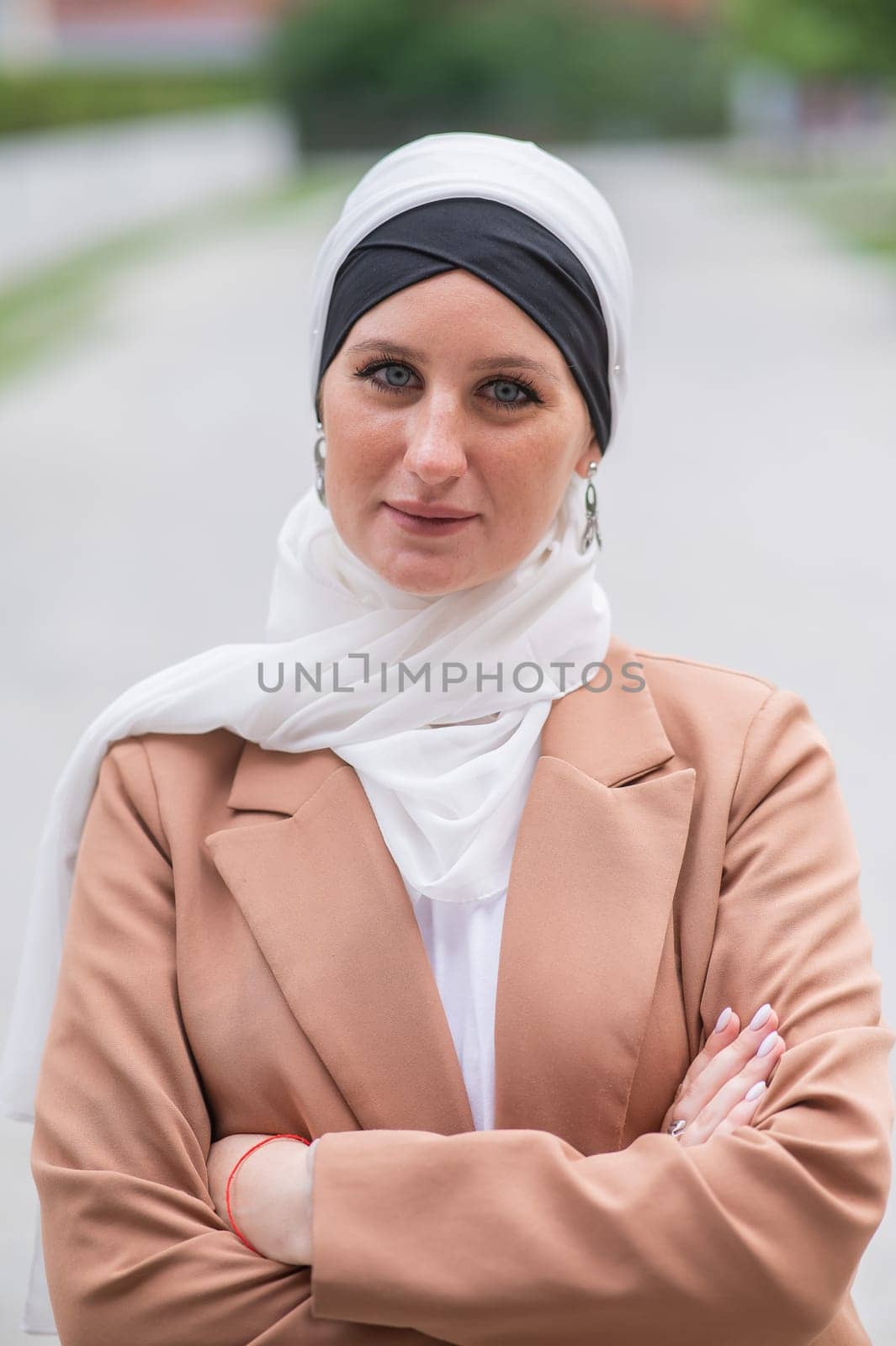 Portrait of a young blue-eyed woman in a hijab outdoors