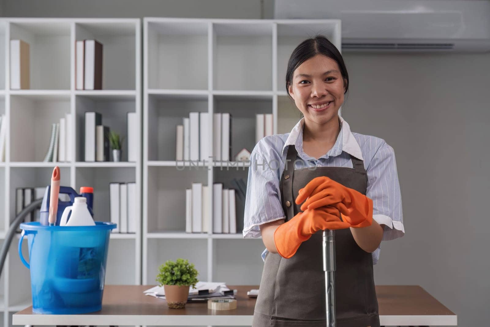 Portrait of a beautiful young housewife smiling and happy, holding cleaning supplies in the office. cleaning supplies, housekeeper by wichayada