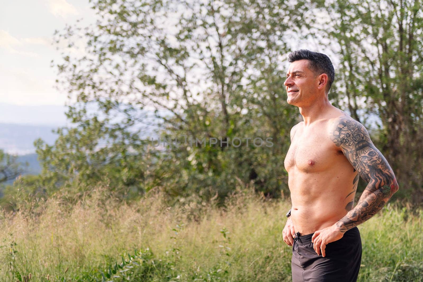 sportsman with fitness body smiling in the countryside, concept of sport in nature and active lifestyle, copy space for text