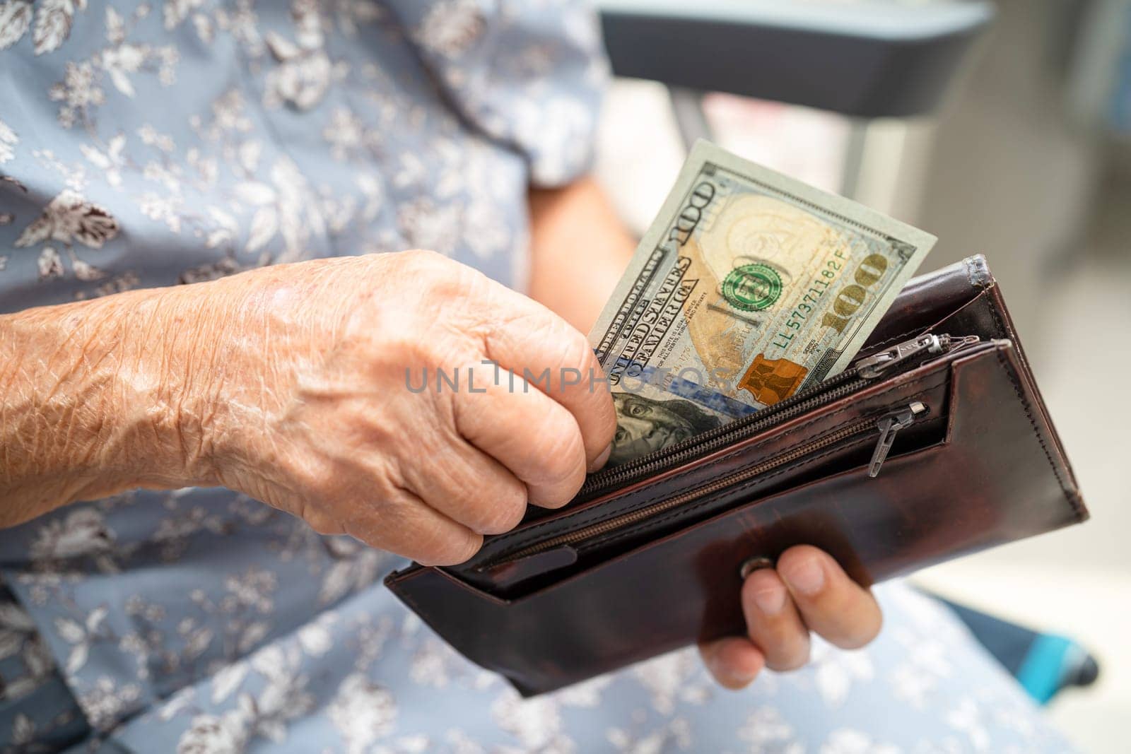 Asian senior woman holding and counting US dollar banknotes money in purse. Poverty, saving problem in retirement.