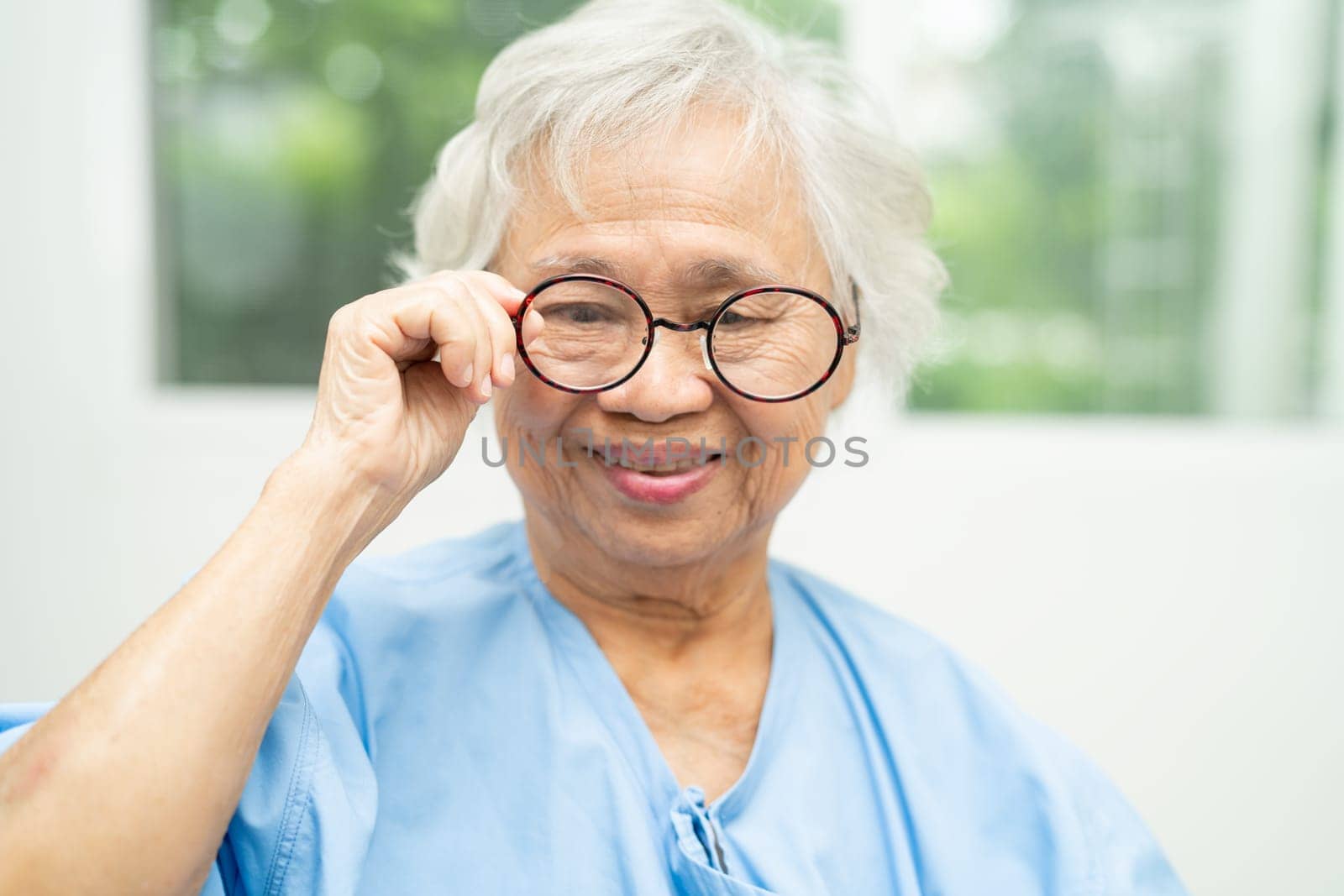 Asian senior woman wearing eyeglasses or vision glasses at home care service. by pamai