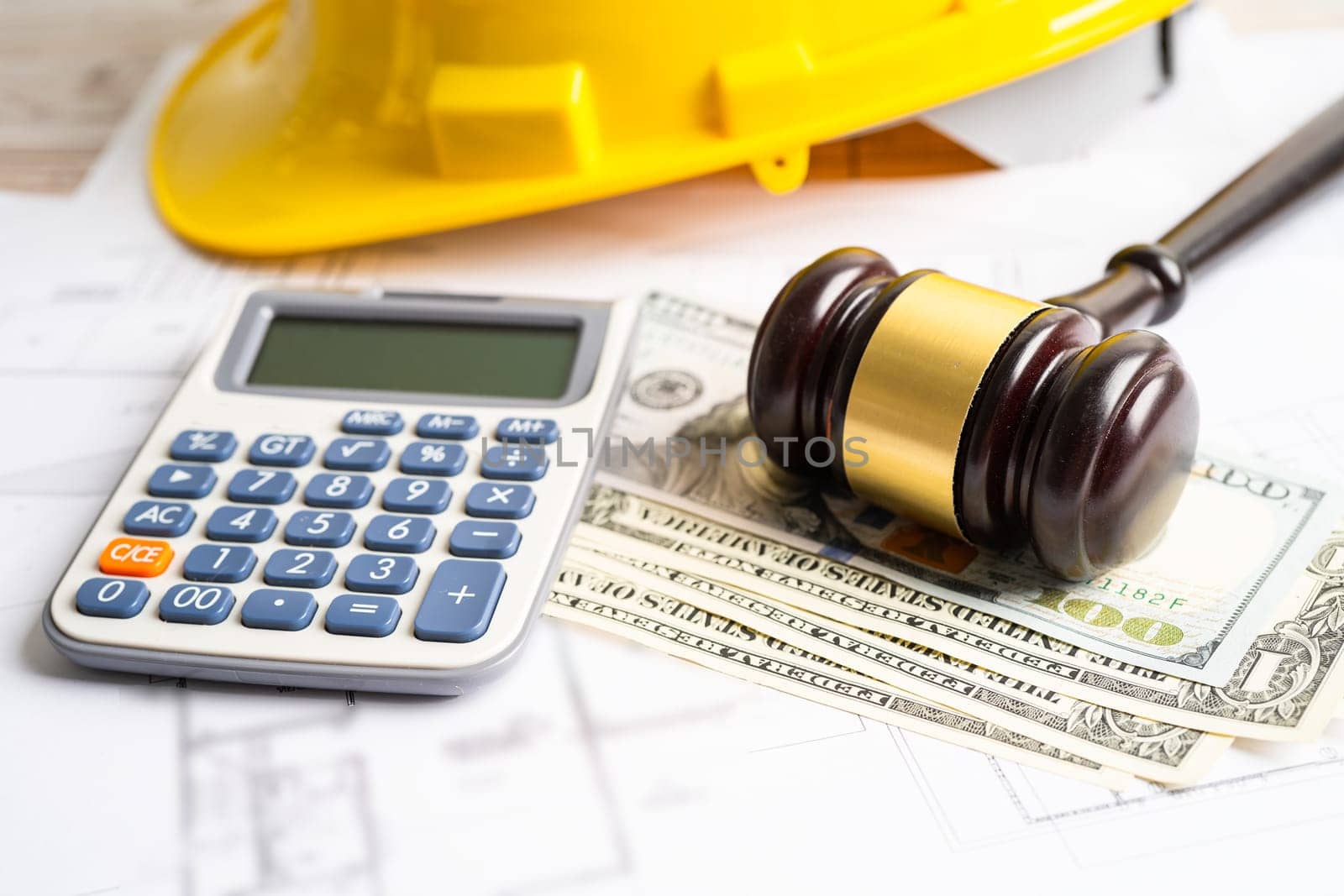 Architectural house plan project blueprint and Judge gavel hammer with yellow helmet and US dollar banknotes, Engineer and construction law and justice.