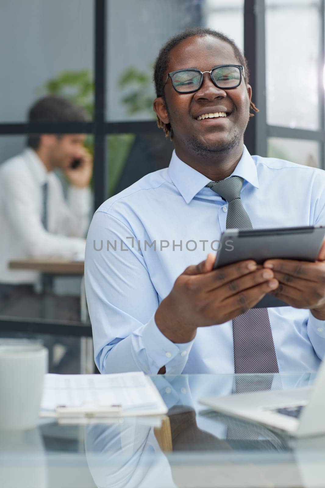 a man at a workplace at a table in front of a computer uses a tablet at office