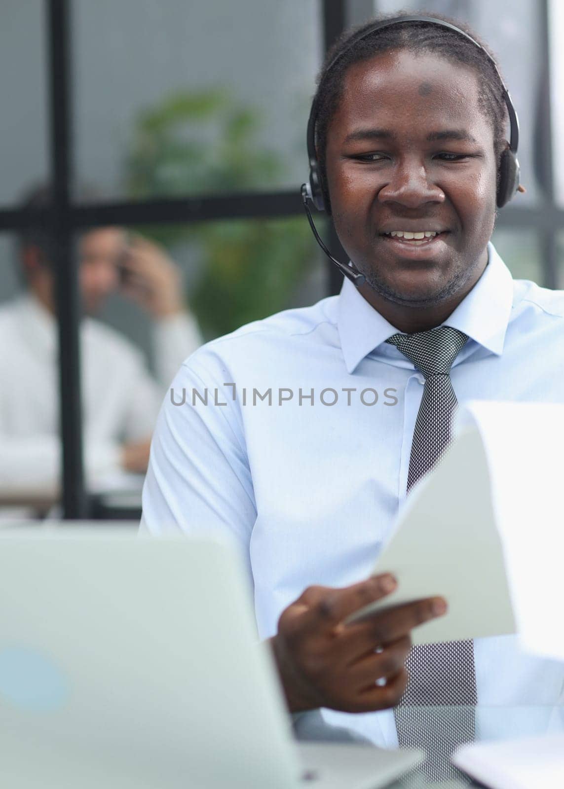 a man at a computer in a call center talking using headphones with a microphone by Prosto