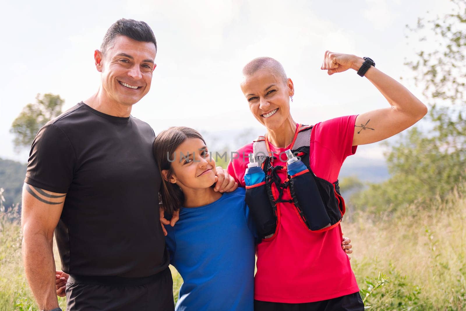 portrait of a sports family smiling happy looking at camera after doing sport in the countryside, concept of active lifestyle and sport with kids in the nature