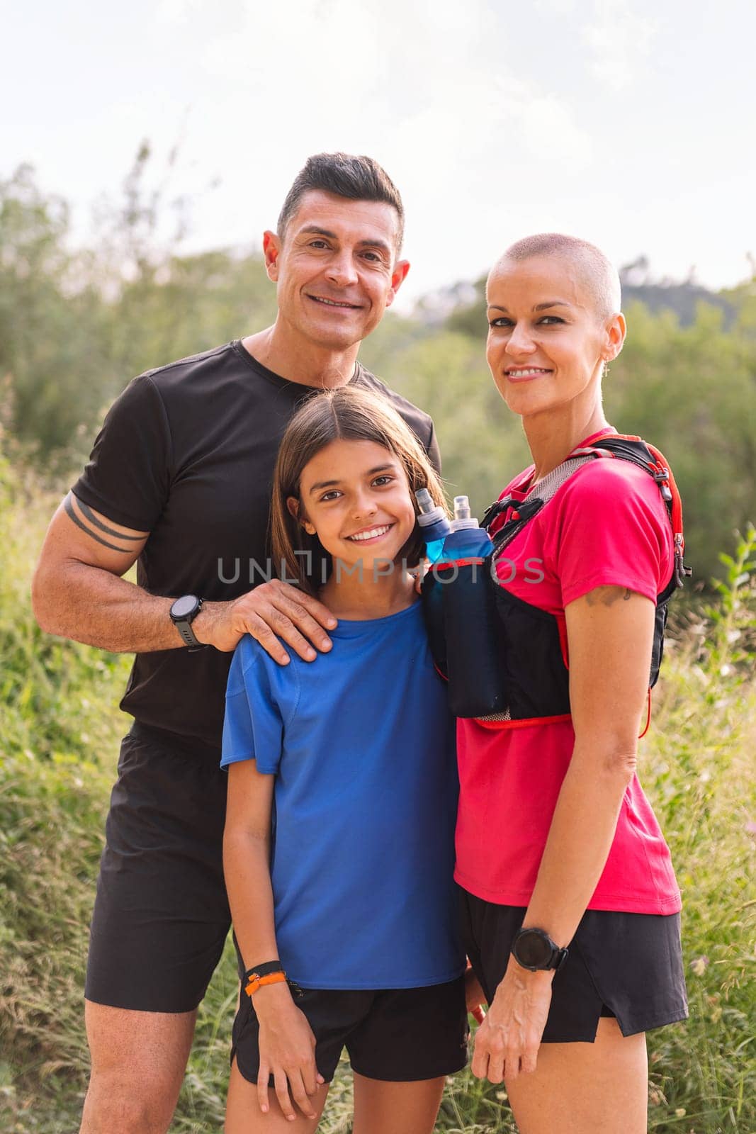 vertical portrait of a happy family looking at camera after doing sports in the countryside, concept of active lifestyle and sport with kids in the nature