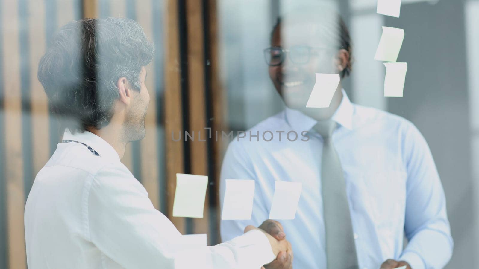 two businessmen discussing business strategy. standing behind the glass looking at stickers.