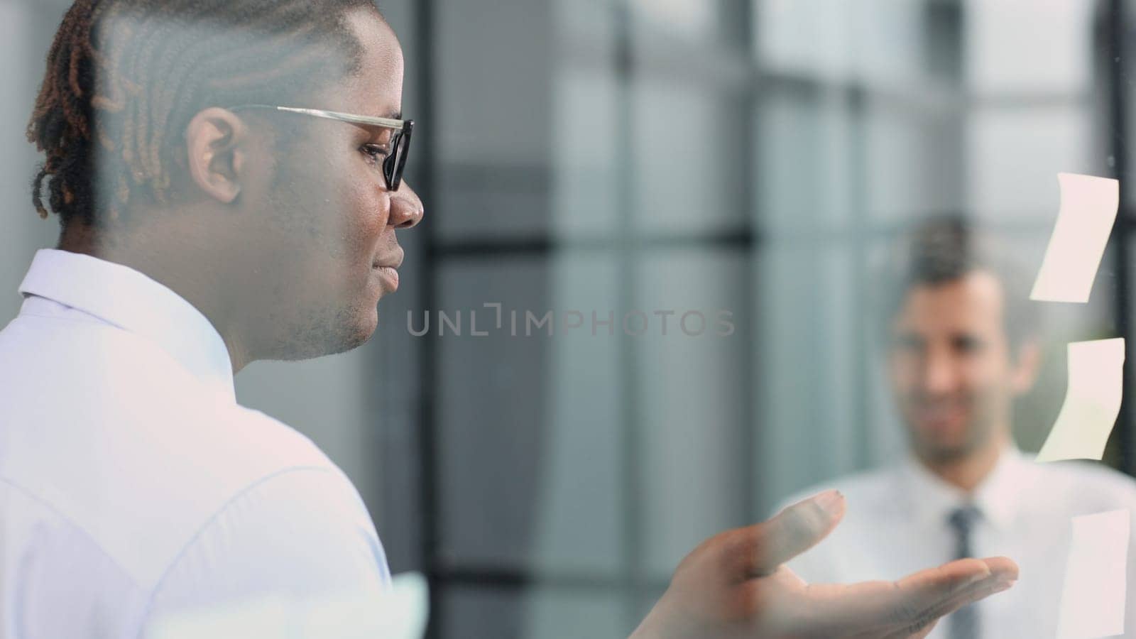 two businessmen discussing business strategy. standing behind the glass looking at stickers by Prosto