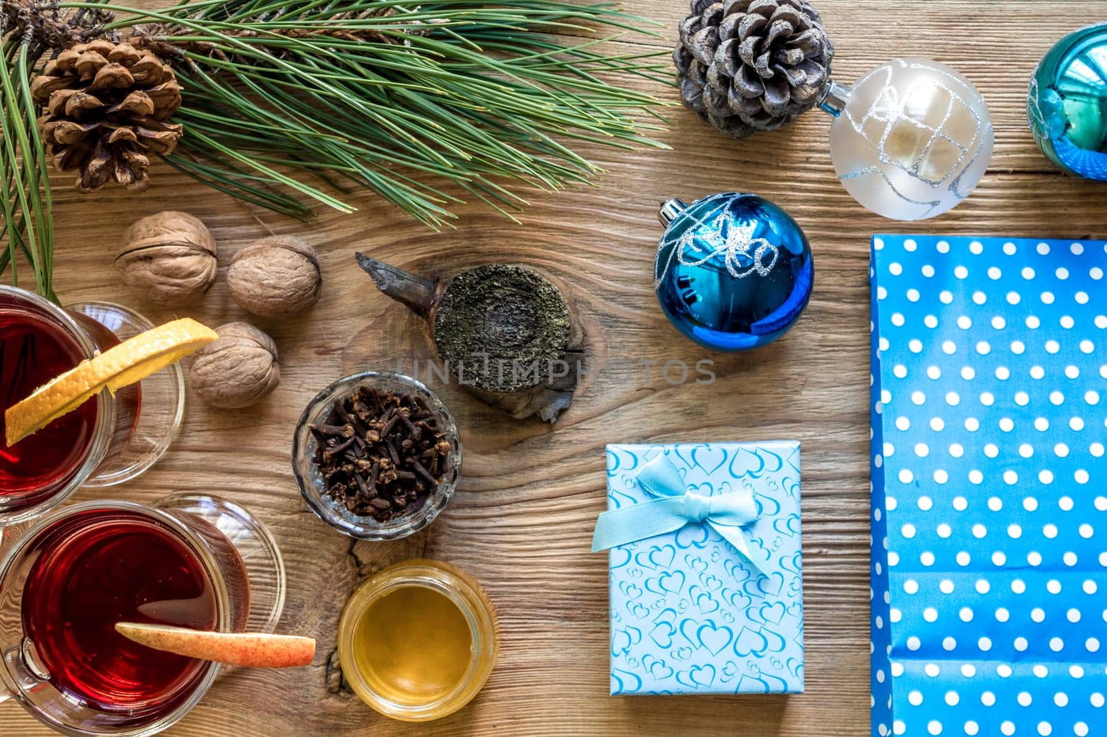 Hot mulled wine with spices on wooden background. Christmas tree branches, gifts and cones. Flat lay, copy space, top view. Holidays.