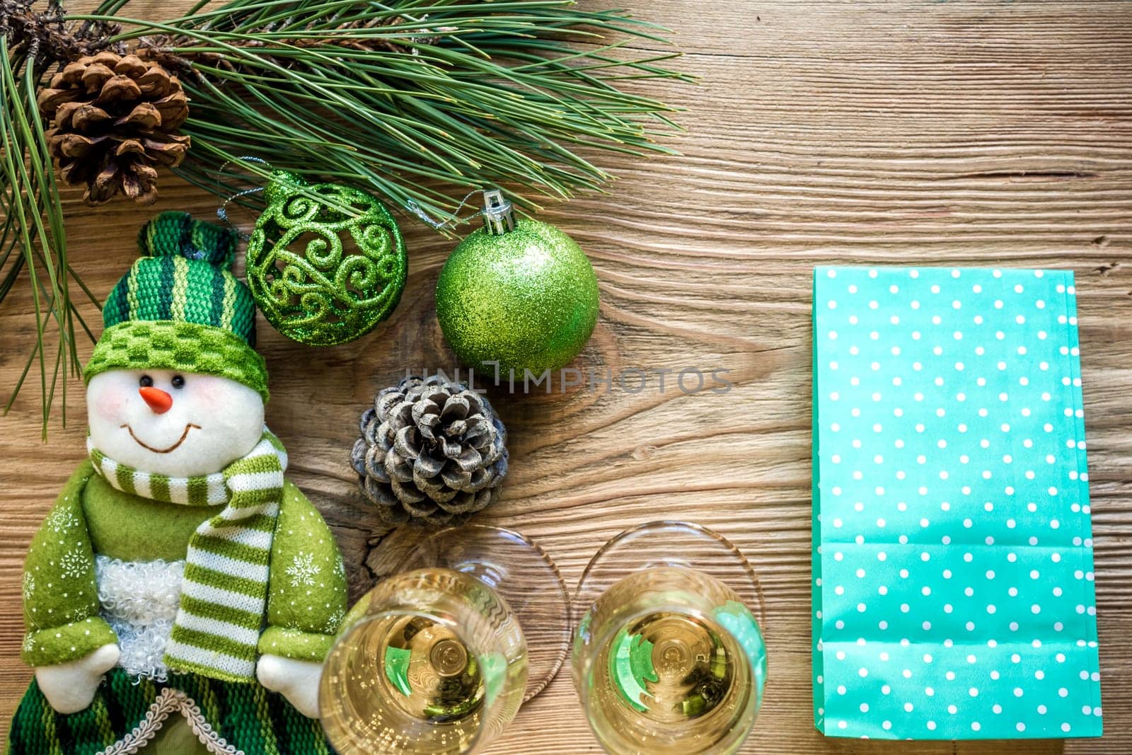 New Year's holiday with spruce branches and with a pair of wine glasses of champagne on wooden background. Flat lay, top view, copy space