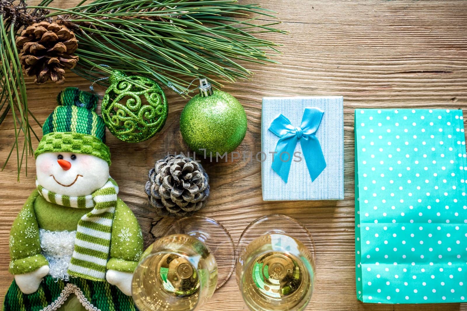 New Year's holiday with spruce branches and with a pair of wine glasses of champagne on wooden background. Flat lay, top view, copy space