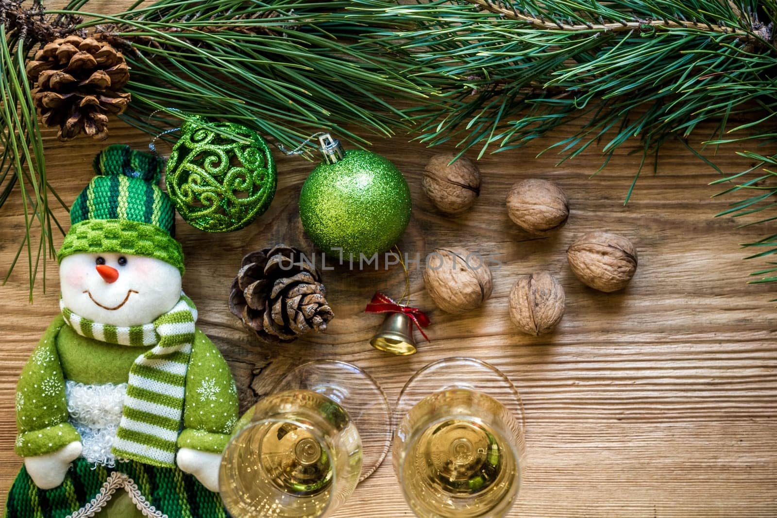 New Year's holiday with spruce branches and with a pair of wine glasses of champagne on wooden background. Flat lay, top view, copy space