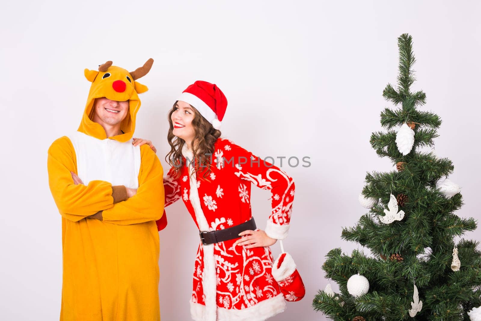 Happy young woman in santa claus hat and man in carnival costume of deer. Fun, holiday, joke and christmas concept.