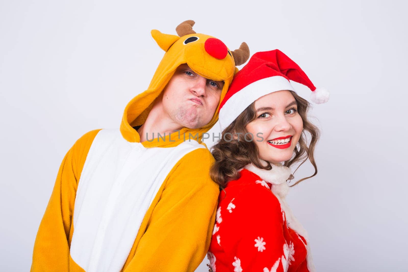 Happy young woman in santa claus hat and man in carnival costume of deer. Fun, holiday, joke and christmas concept.