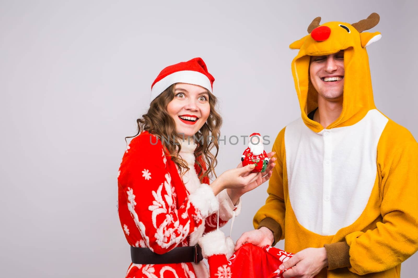 Happy young woman in santa claus hat and man in carnival costume of deer. Fun, holiday, joke and christmas concept.