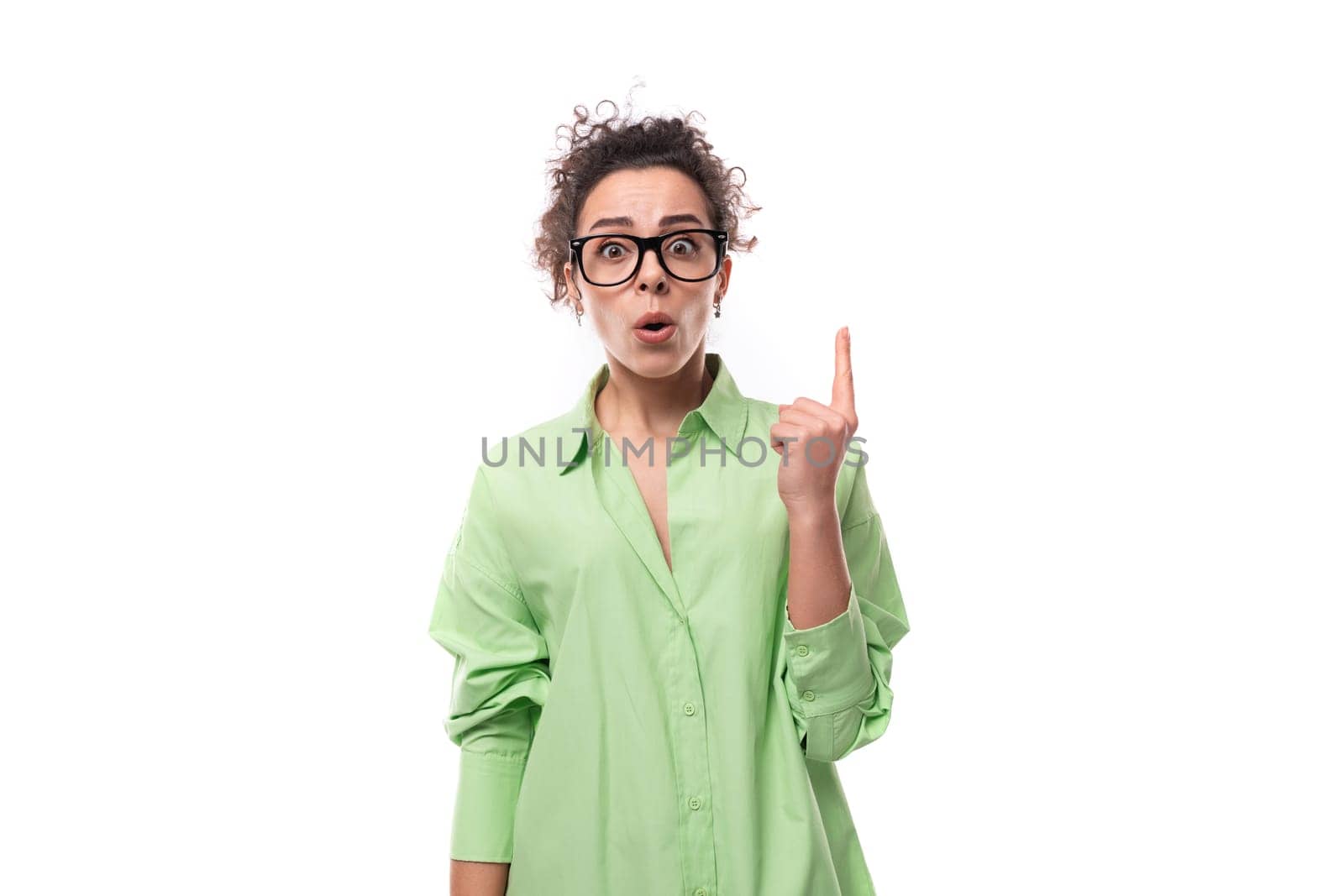 young stylish caucasian secretary woman with black curly hair in glasses and light green shirt on a white background with copy space.