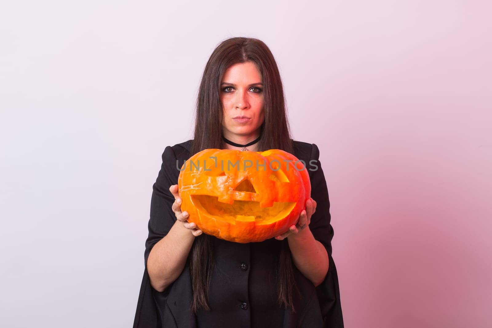 Gothic young woman in witch halloween costume with a carved pumpkin by Satura86
