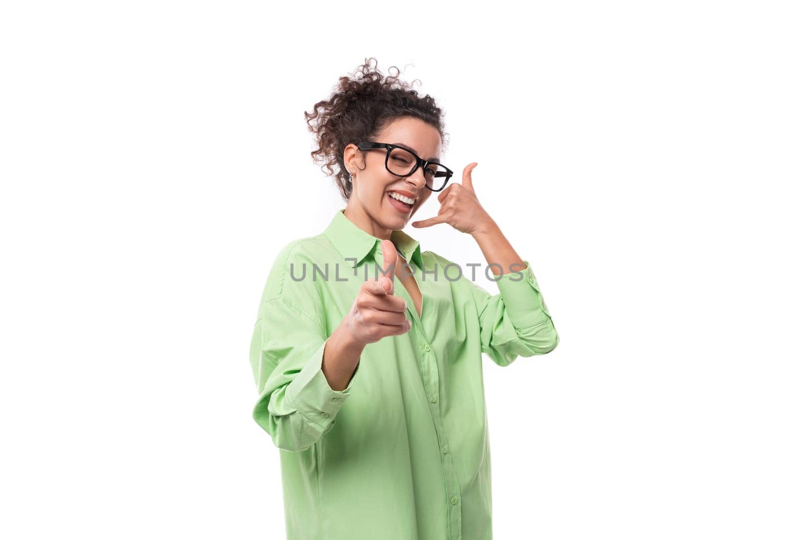 young caucasian woman with black curly hair wearing glasses and light green shirt on a white background with copy space by TRMK