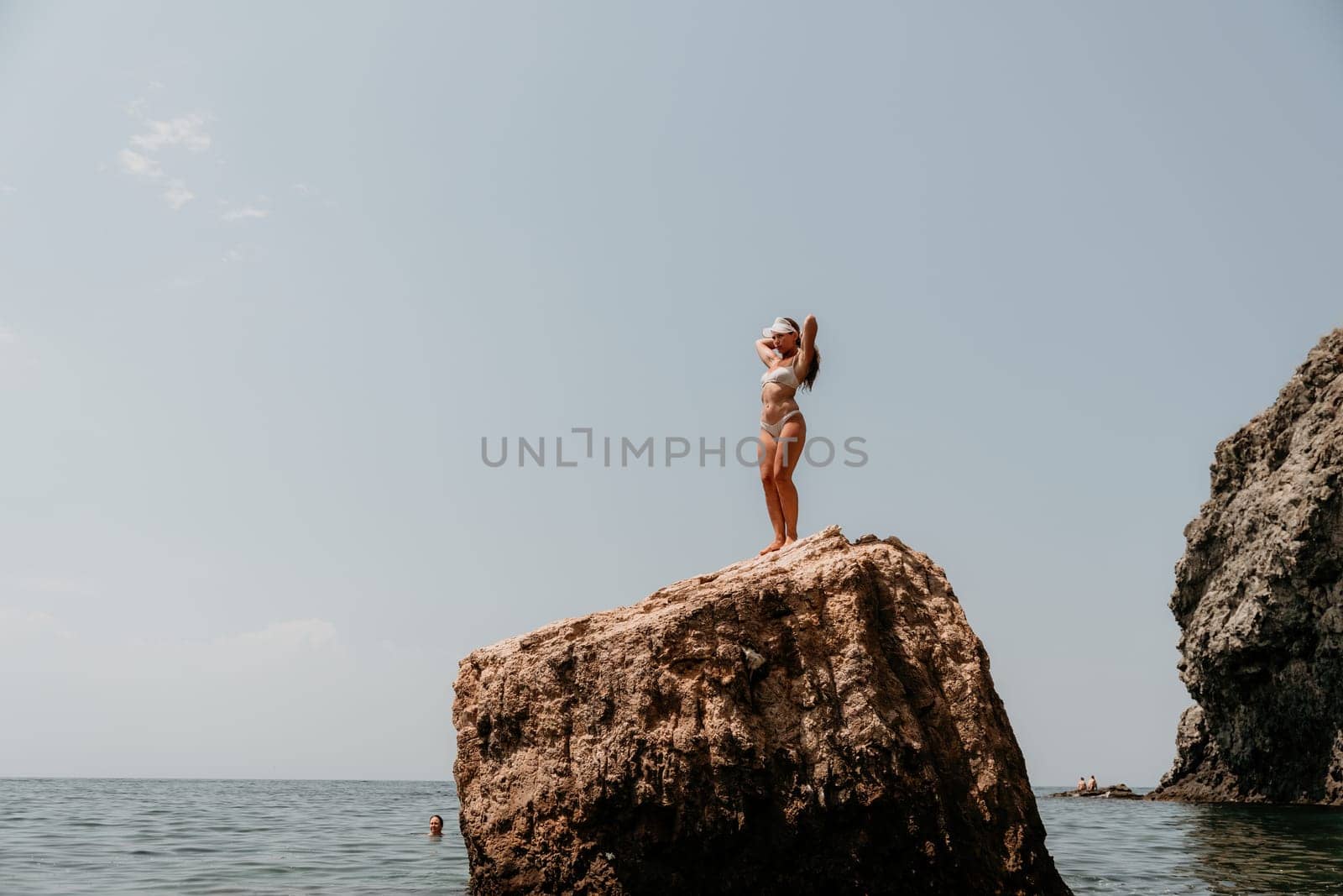 Woman meditating in yoga pose silhouette at the ocean, beach and rock mountains. Motivation and inspirational fit and exercising. Healthy lifestyle outdoors in nature, fitness concept.