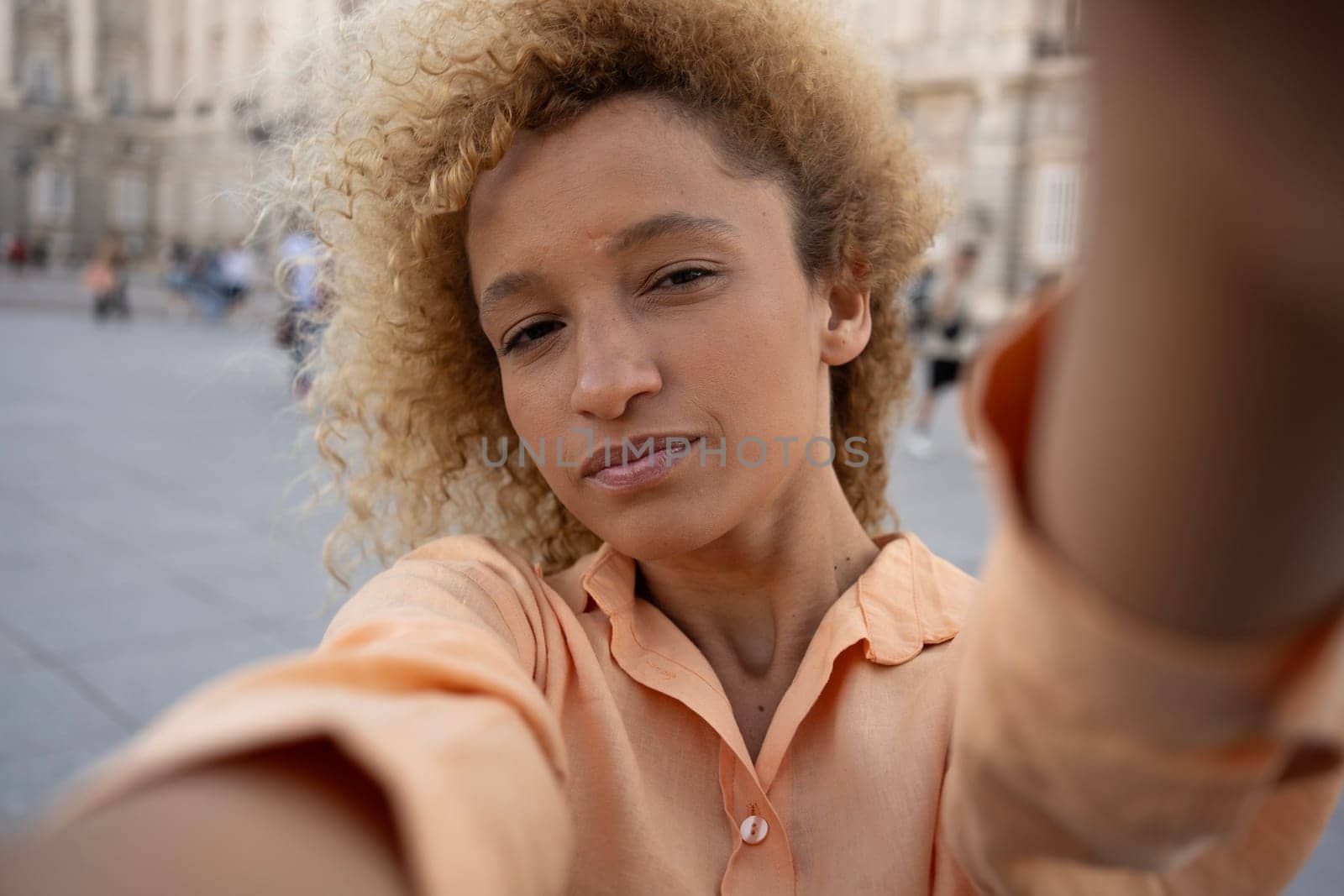 Latin young woman enjoying taking selfie with smartphone while visiting in Madrid city.