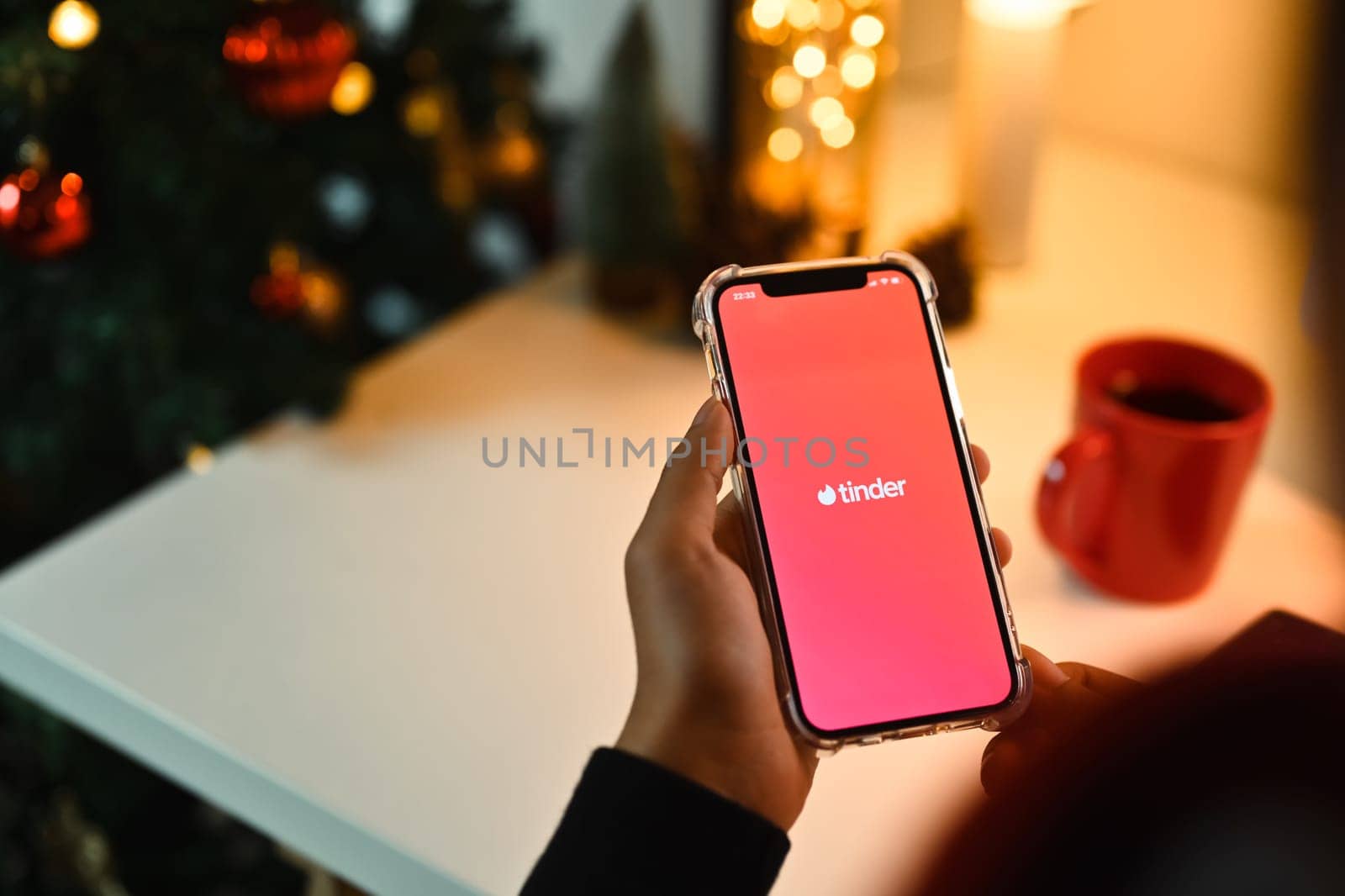 Chiang Mai, Thailand - Oct 31,2023: Woman holding smart phone with Tinder app in screen. Tinder is a application for online romantic dating by prathanchorruangsak