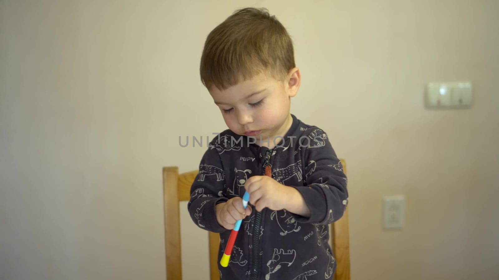 A little boy closes the cap of a felt-tip pen. Child with a felt-tip pen. 4k