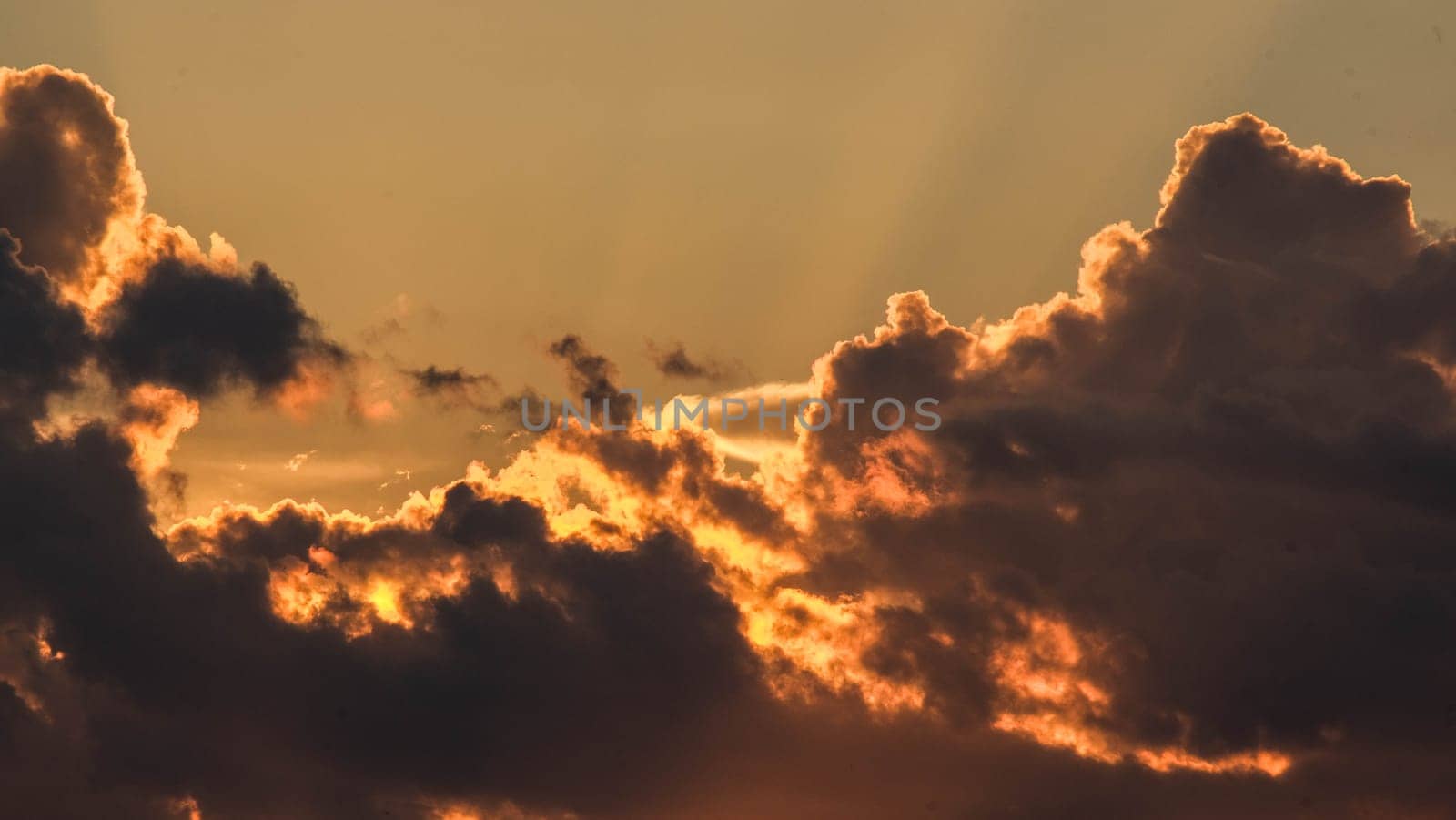 Beautiful dramatic sky with clouds at sunset or sunrise. Sunset sky at dusk in the evening with natural sky background with golden orange clouds. by TEERASAK