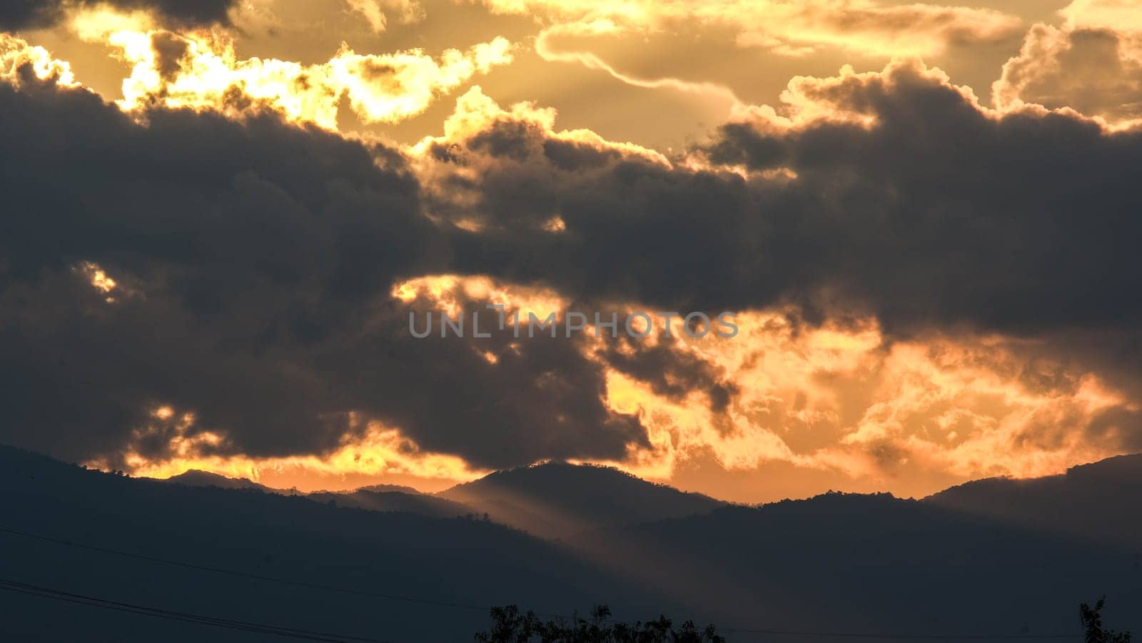 Beautiful dramatic sky with clouds at sunset or sunrise. Sunset sky at dusk in the evening with natural sky background with golden orange clouds. by TEERASAK