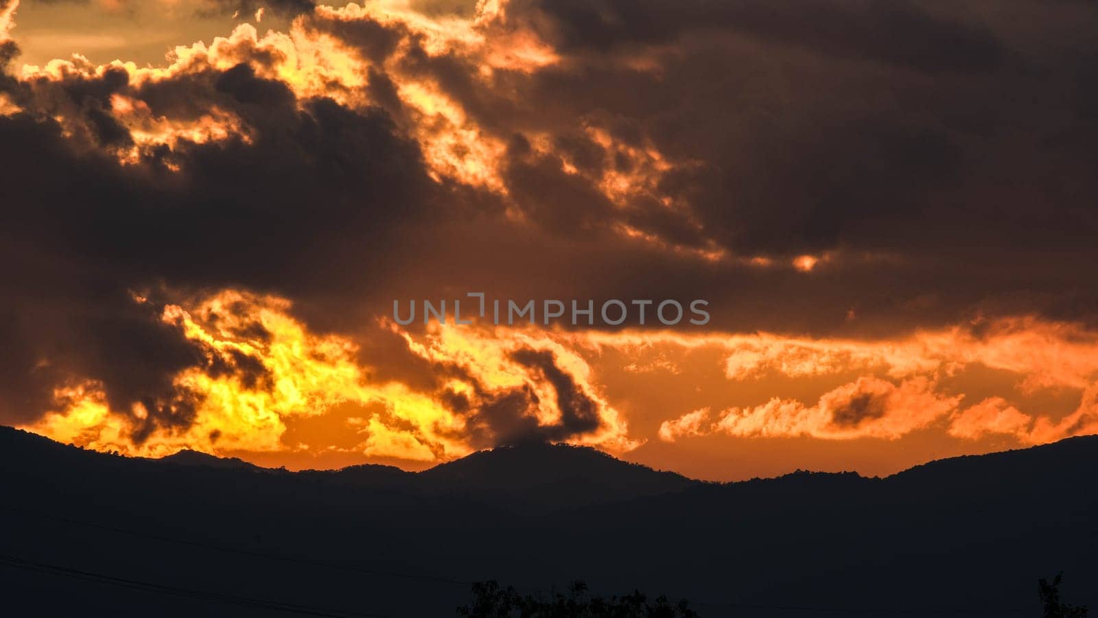 Beautiful dramatic sky with clouds at sunset or sunrise. Sunset sky at dusk in the evening with natural sky background with golden orange clouds. by TEERASAK