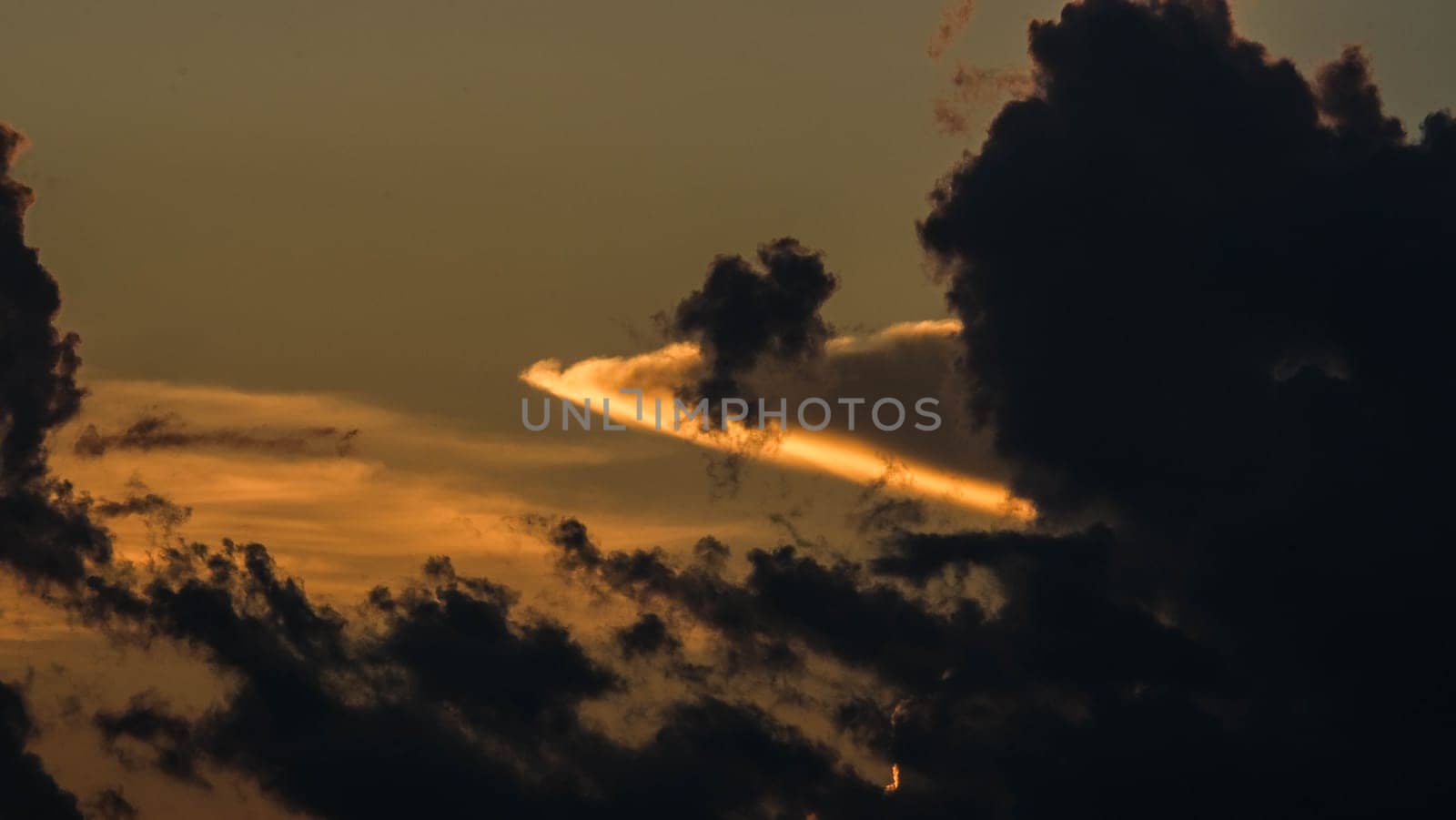 Beautiful dramatic sky with clouds at sunset or sunrise. Sunset sky at dusk in the evening with natural sky background with golden orange clouds.