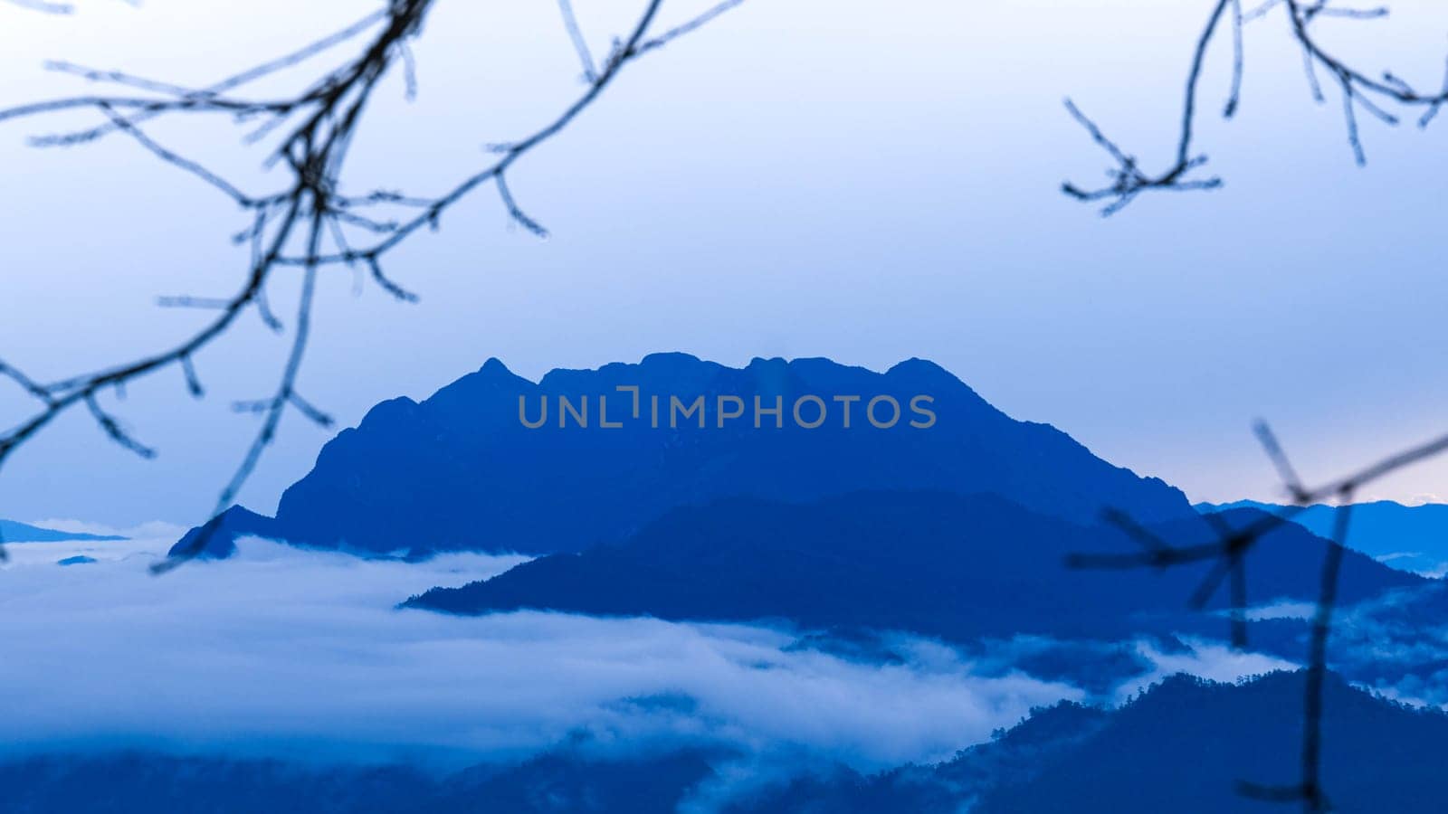 Aerial view over the mountains with sea of fog during morning sunrise in blue sky. Sea of clouds around mountain peaks at sunrise. Unseen travel in Northern Thailand. by TEERASAK