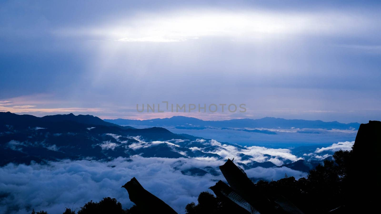 Aerial view over the mountains with sea of fog during morning sunrise in blue sky. Sea of clouds around mountain peaks at sunrise. Unseen travel in Northern Thailand. by TEERASAK