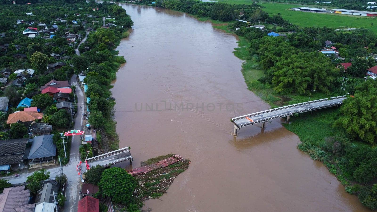 Aerial view of a damaged road bridge over a river after floodwaters washed away the asphalt. Broken bridge after flash floods in the rainy season.
