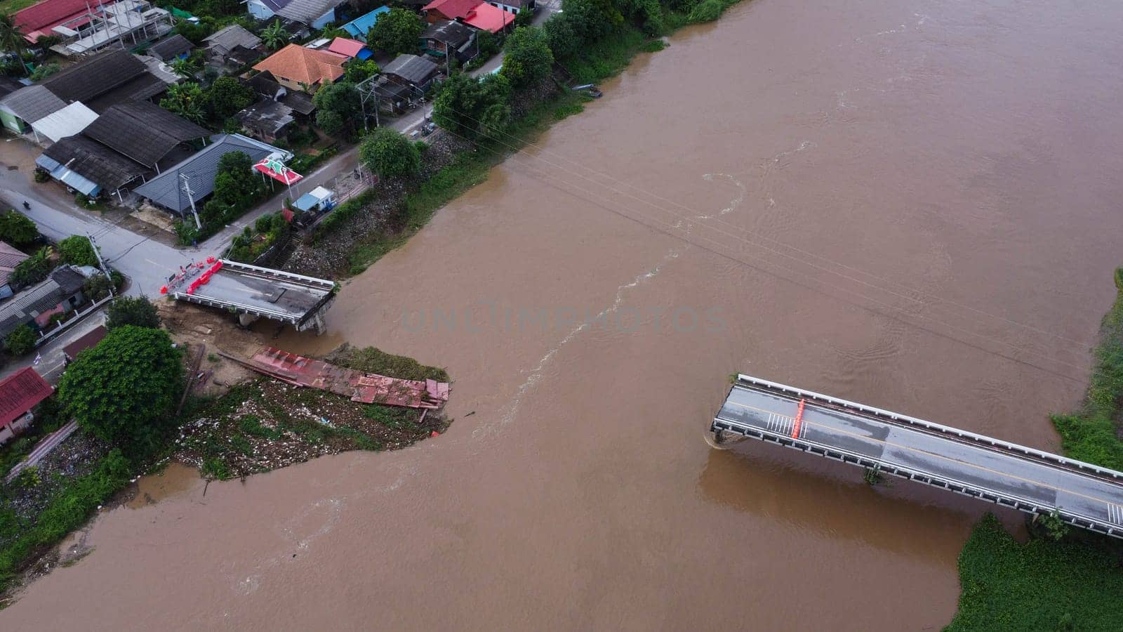 Aerial view of a damaged road bridge over a river after floodwaters washed away the asphalt. Broken bridge after flash floods in the rainy season. by TEERASAK