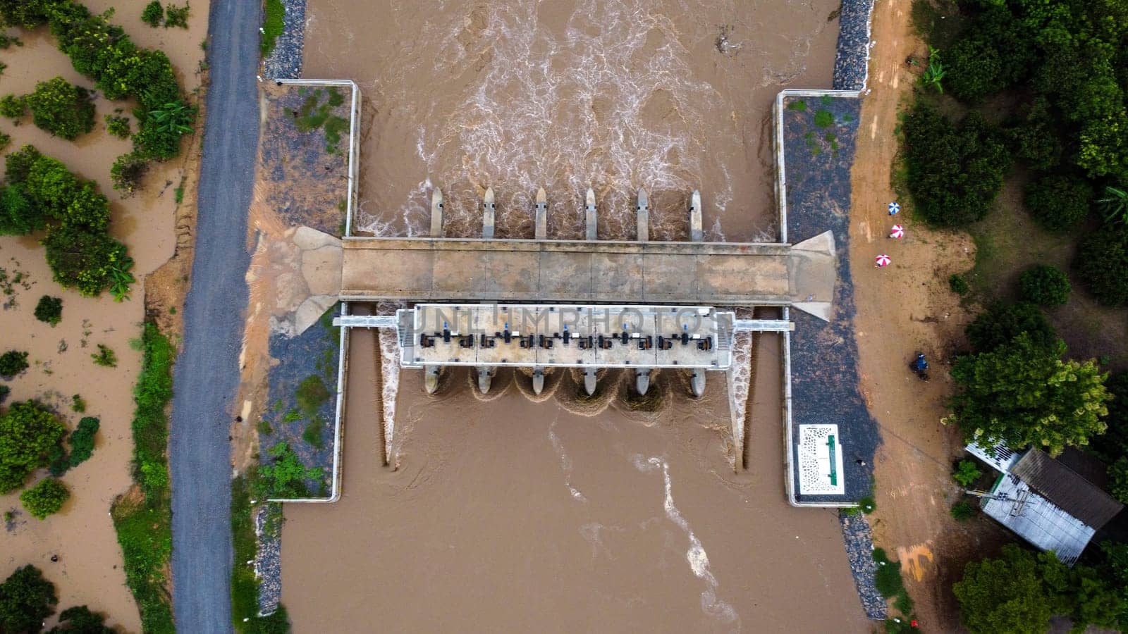 Aerial view of water released from the drainage channel of the concrete dam is a way of overflowing water in the rainy season. Top view of turbid brown forest water flows from a dam in Thailand.