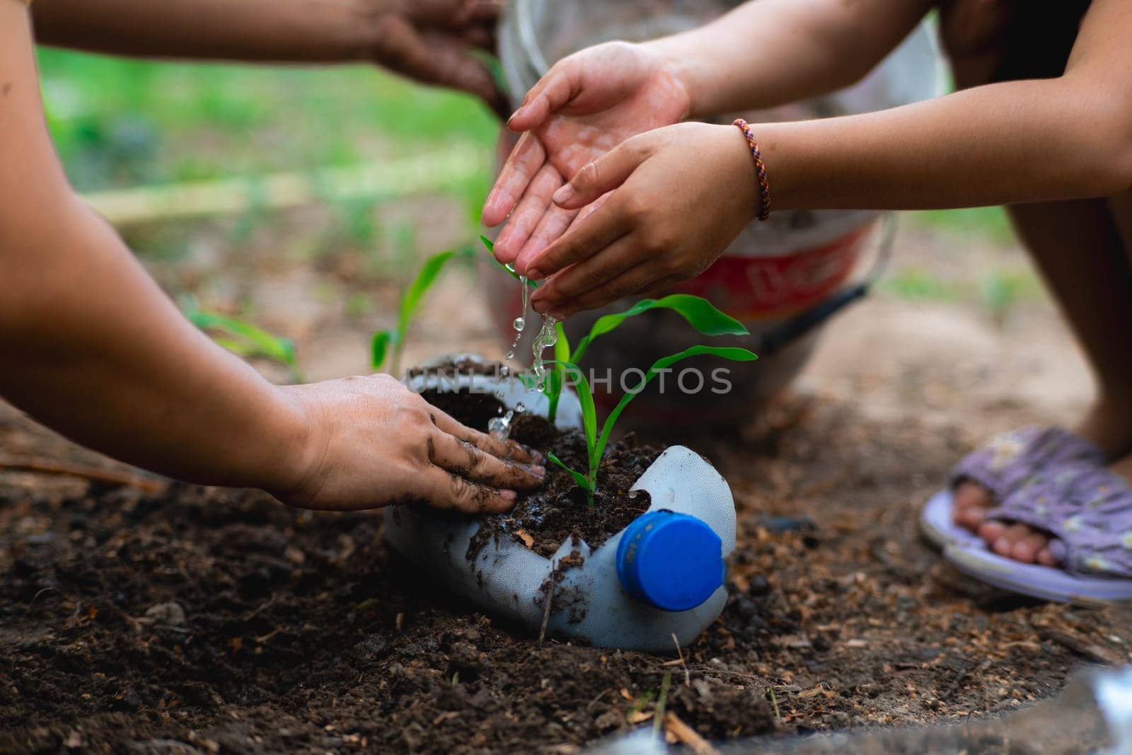 Little girl and mom grow plants in pots from recycled water bottles in the backyard. Recycle water bottle pot, gardening activities for children. Recycling of plastic waste