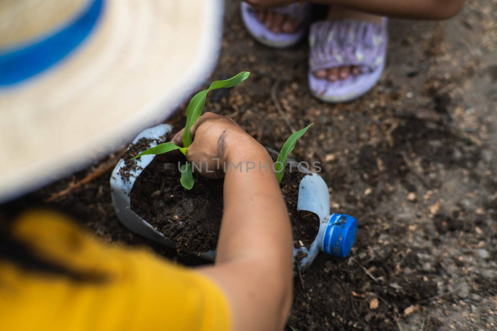 Little girl and mom grow plants in pots from recycled water bottles in the backyard. Recycle water bottle pot, gardening activities for children. Recycling of plastic waste