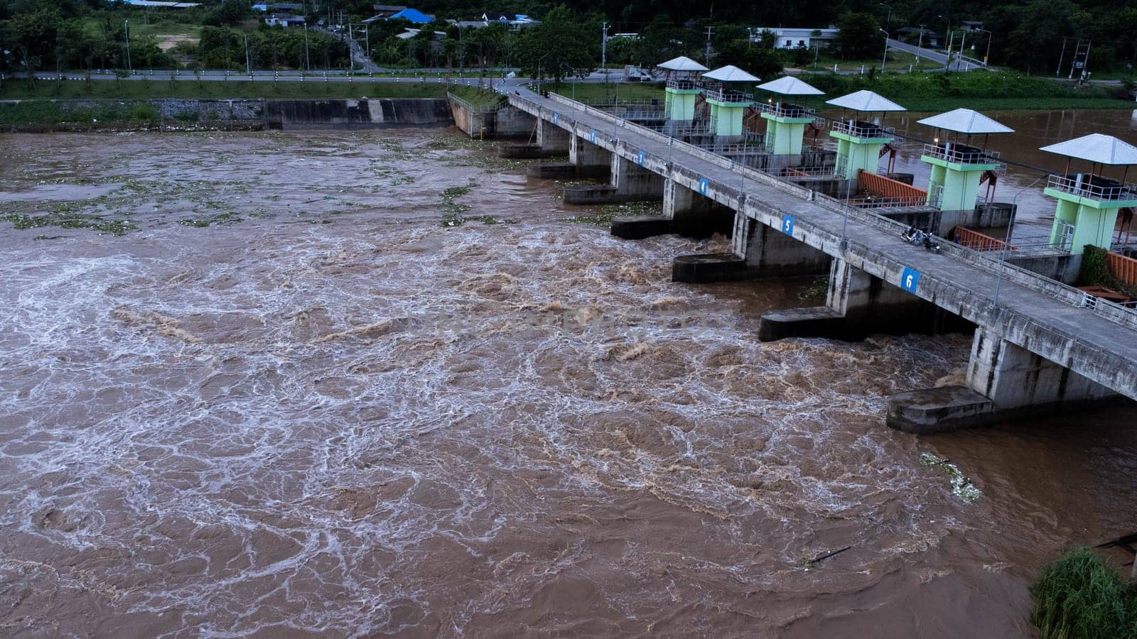 Aerial view of water released from the drainage channel of the concrete dam is a way of overflowing water in the rainy season. Top view of turbid brown forest water flows from a dam in Thailand.