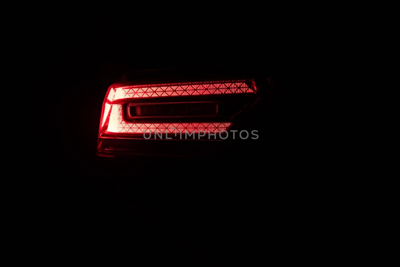 Car back lights shining. Close up detail on one of the LED red taillight modern luxury car. Exterior detail automobile. Tail light car. Detail on the rear light of a car by uflypro