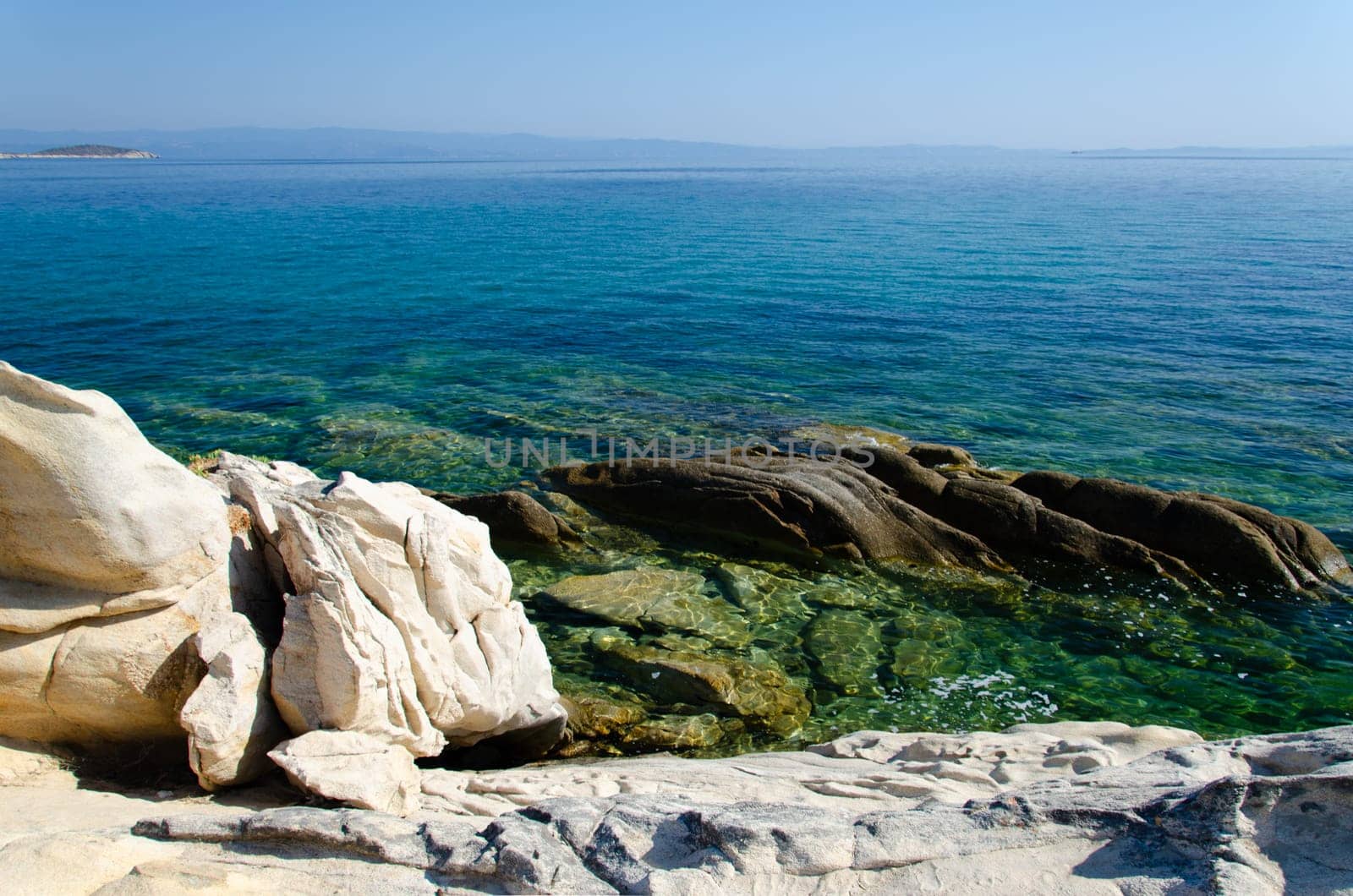 White stone shore and azure sea. Karidi Beach, Halkidiki. You can see the rocky bottom in the clear water.