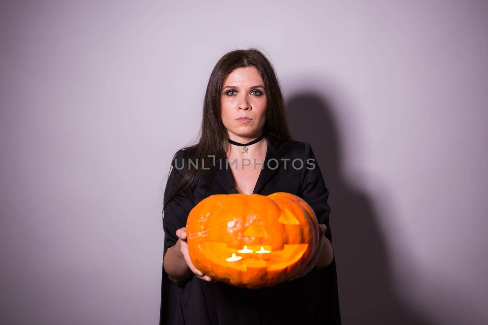 Jack o Lantern Halloween pumpkin grinning in the most evil fashion in woman's hands