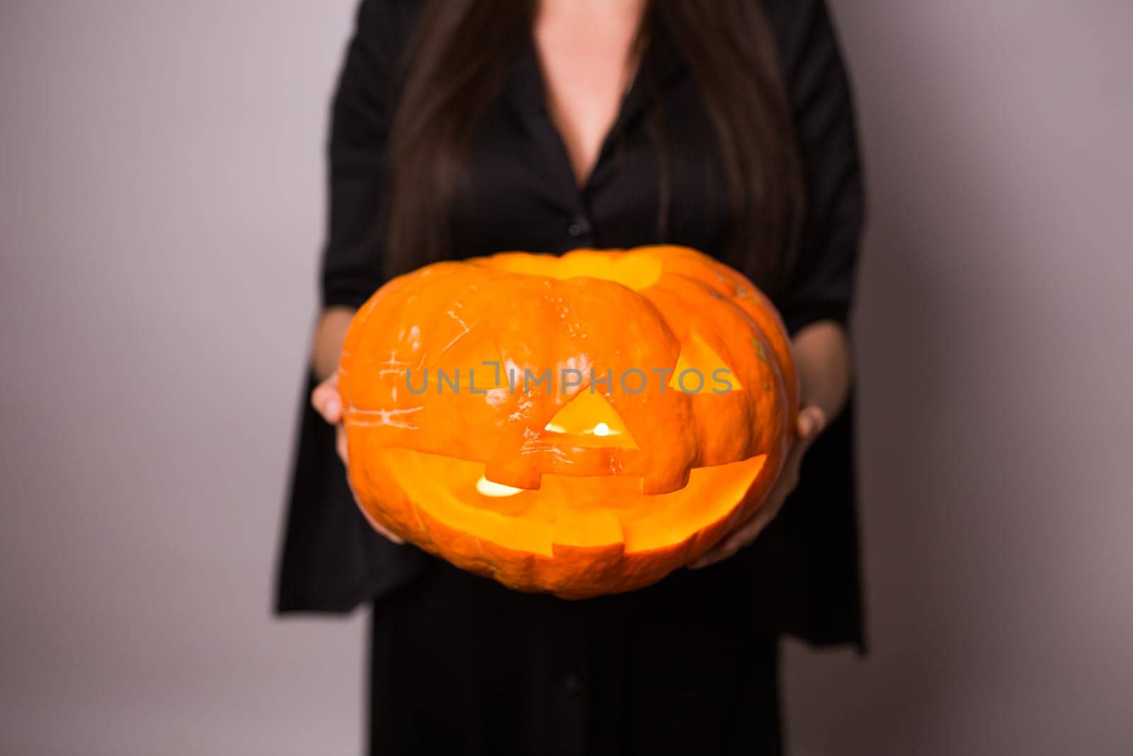 Jack o Lantern Halloween pumpkin grinning in the most evil fashion in woman's hands. by Satura86