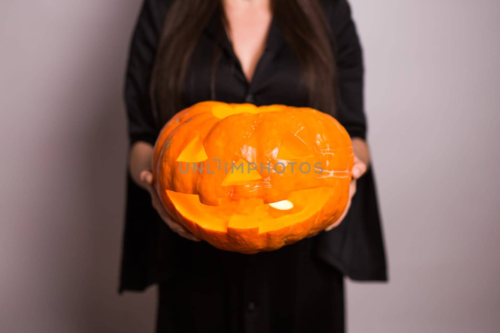 Jack o Lantern Halloween pumpkin grinning in the most evil fashion in woman's hands