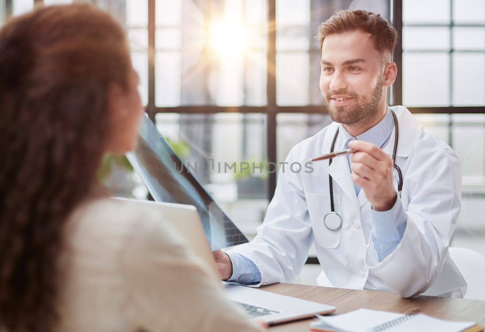 Young serious competent male doctor looking at X-ray at doctor's office