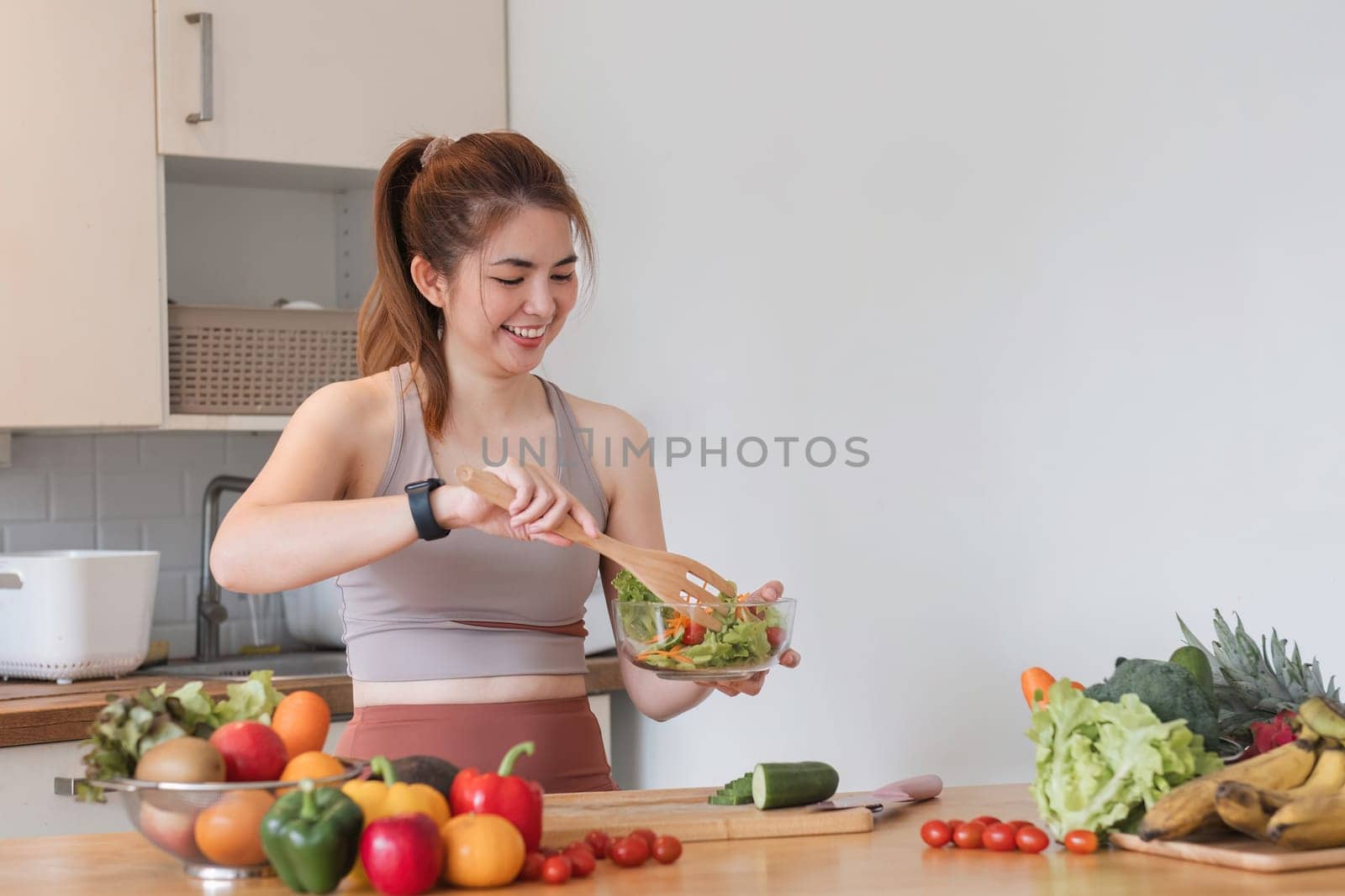 Young athletic woman is preparing a healthy organic vegetable salad in a modern kitchen at home..
