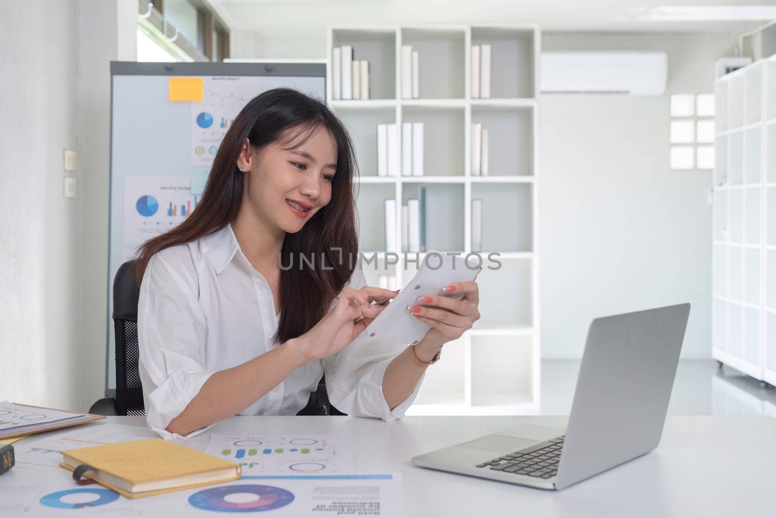 Businesswoman using calculator to do finance, mathematics on white table in office and business background, graph, tax, accounting, statistics and analytical research concept..